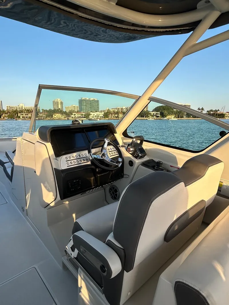 Slide: The Image of 2024 Crownline 260DC boat cockpit with steering wheel, dashboard, and waterfront view. - 6
