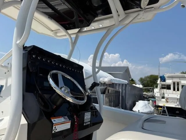 Slide: The Image of 2018 Wellcraft 222 Fisherman boat dashboard with steering wheel, docked under clear blue sky. - 7