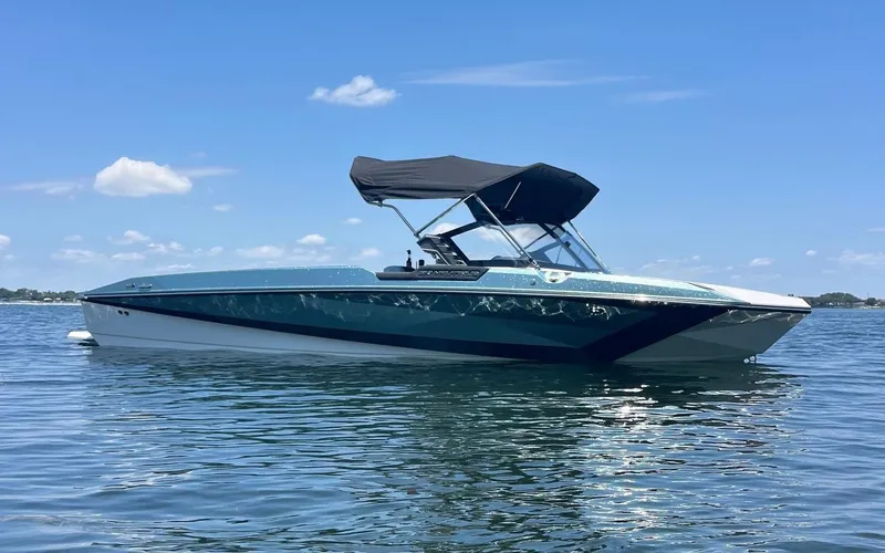 Slide: The Image of 2025 Nautique Ski boat on calm water under a clear blue sky. - 10