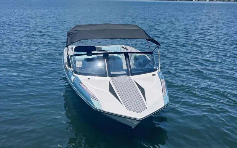 Slide: The Image of 2025 Nautique Ski boat on calm water, featuring sleek design and canopy. - 2