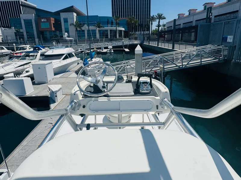 Slide: The Image of 2007 Boston Whaler 320 Outrage helm at marina, surrounded by boats and modern buildings. - 20