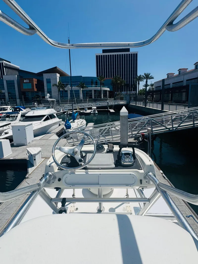 Slide: The Image of 2007 Boston Whaler 320 Outrage at marina, surrounded by boats and modern buildings. - 21