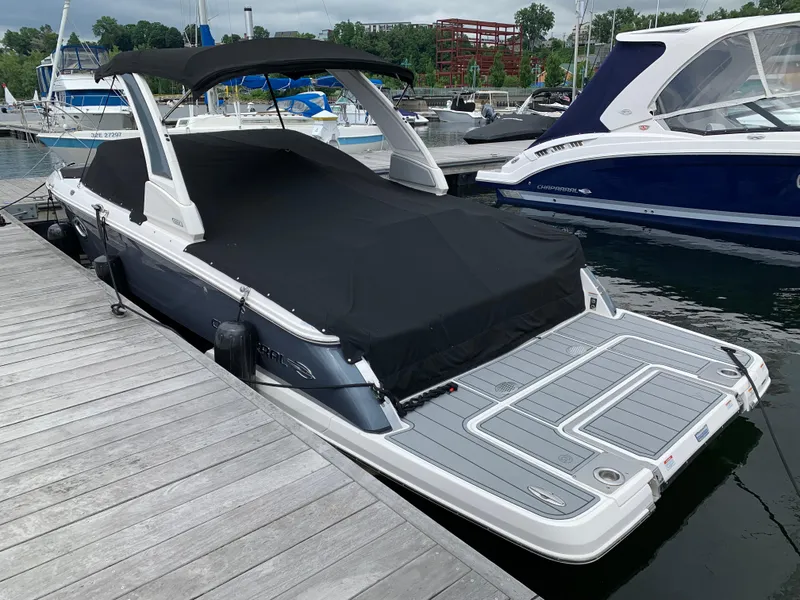 Slide: The Image of 2021 Chaparral 267 SSX boat docked with black cover, marina background. - 23