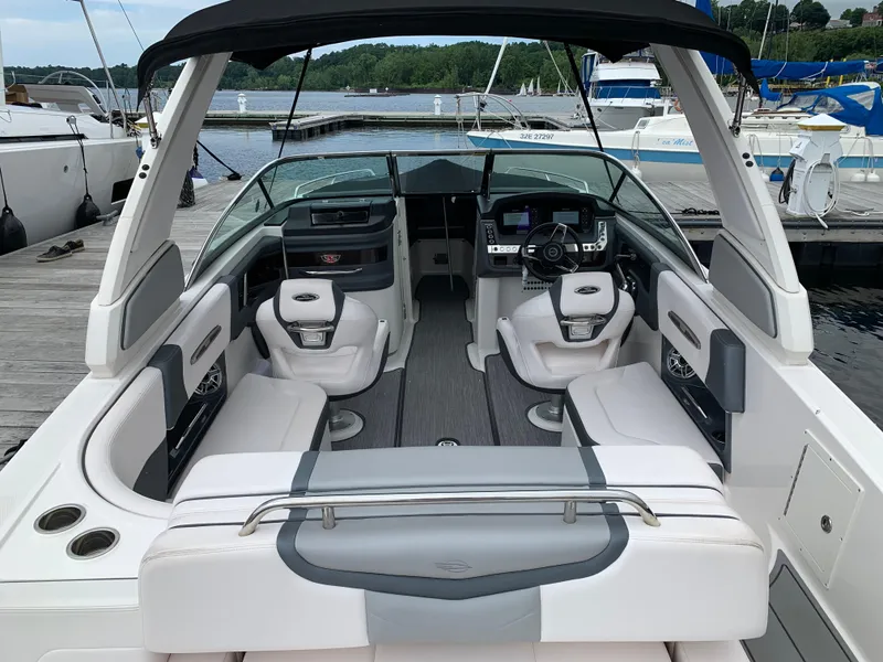 Slide: The Image of 2021 Chaparral 267 SSX boat interior with seating and dashboard at a marina. - 28