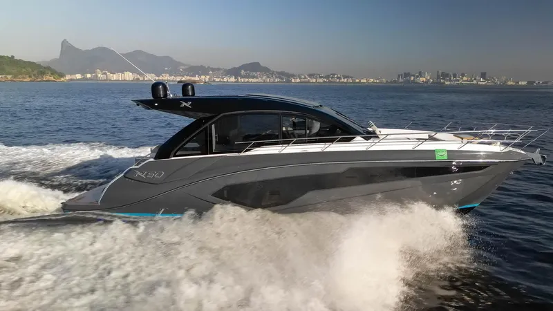The Image of 2025 NX Boats NX50 Invictus HT cruising on open water with cityscape in background. - 1
