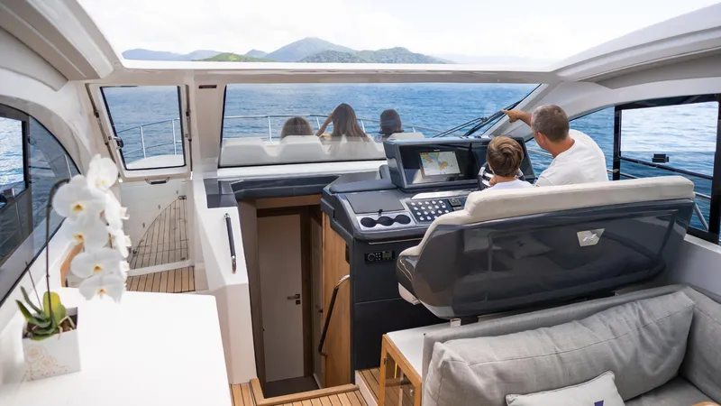 Slide: The Image of 2025 NX Boats NX50 Invictus HT interior with modern helm, passengers, and scenic ocean view. - 25
