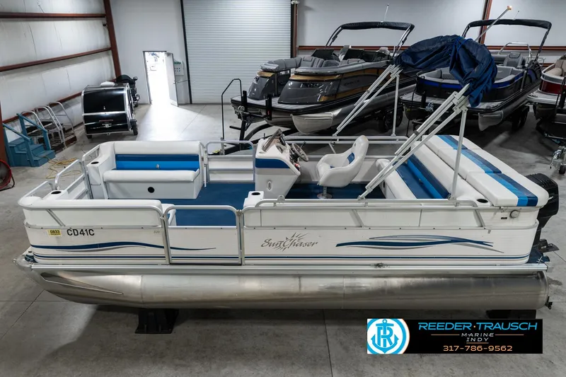 Slide: The Image of 2005 SunChaser 820 pontoon boat in showroom, featuring blue and white seating. - 1