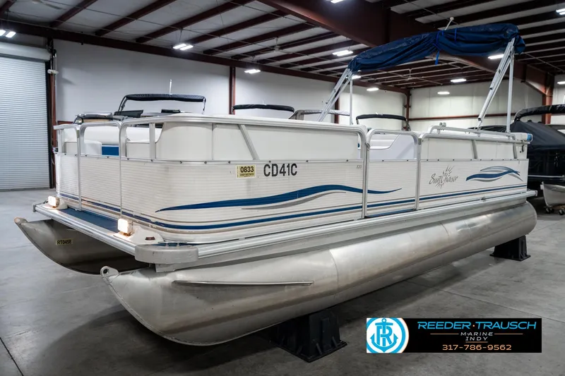 Slide: The Image of 2005 SunChaser 820 pontoon boat in indoor storage, featuring blue accents and canopy. - 3