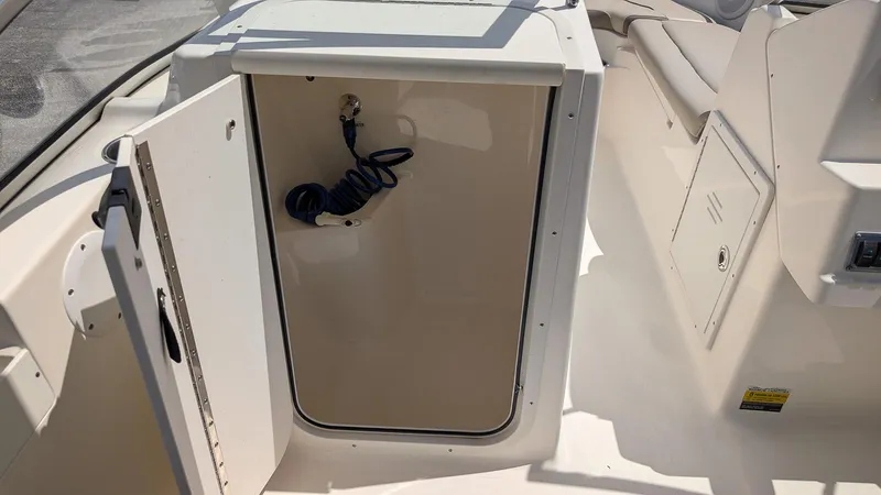 Slide: The Image of Open storage compartment on a 2021 Key West 203 DFS boat, featuring coiled hose. - 16