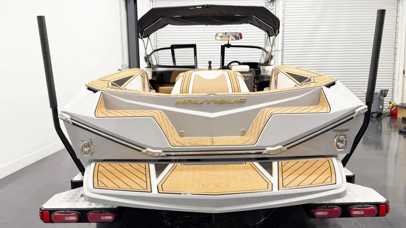 Slide: The Image of 2025 Nautique Ski boat rear view in a garage, featuring sleek design and wood accents. - 4