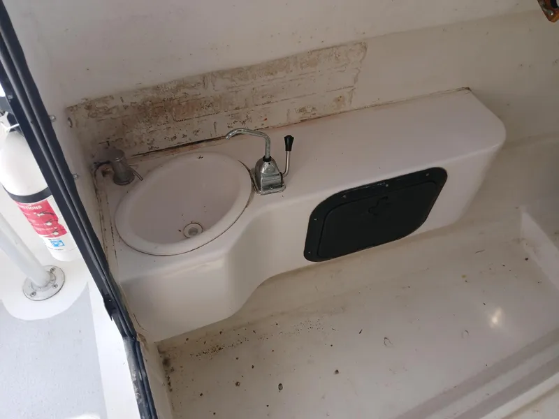 Slide: The Image of 2005 Twin Vee 26 Weekender boat sink area with faucet and storage compartment. - 5