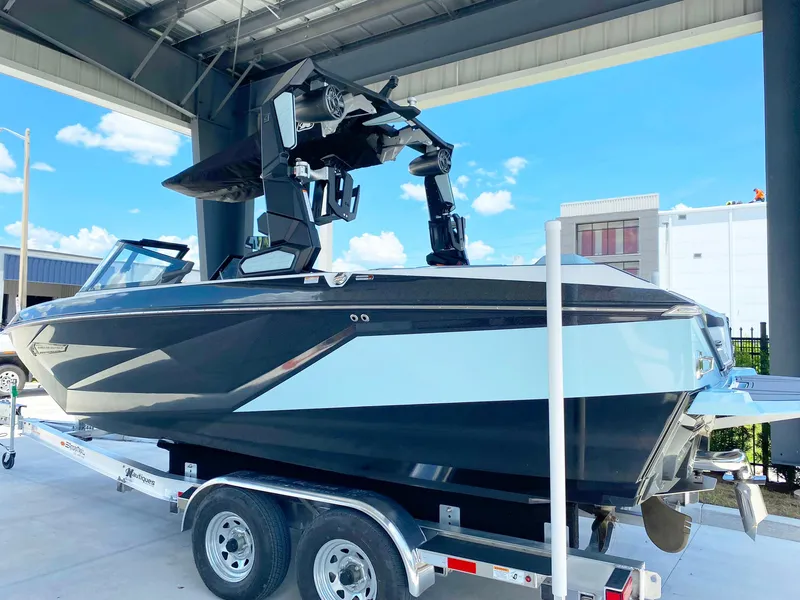 Slide: The Image of 2024 Nautique Super Air Nautique G21 boat on trailer under a metal roof. - 3