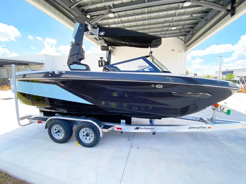 Slide: The Image of 2024 Nautique Super Air Nautique G21 boat on trailer under a metal canopy. - 6