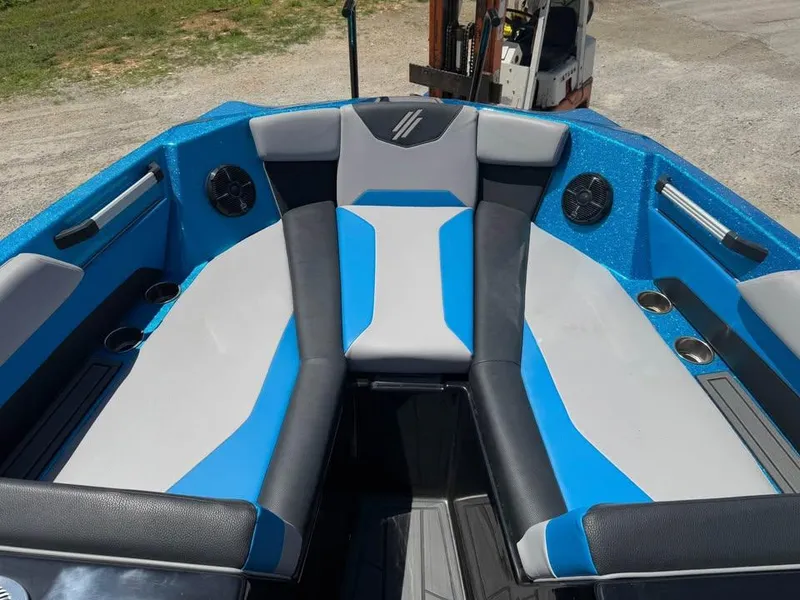 Slide: The Image of 2023 ATX Surf Boats 24 Type-S interior with blue and gray seating, cup holders, and speakers. - 12
