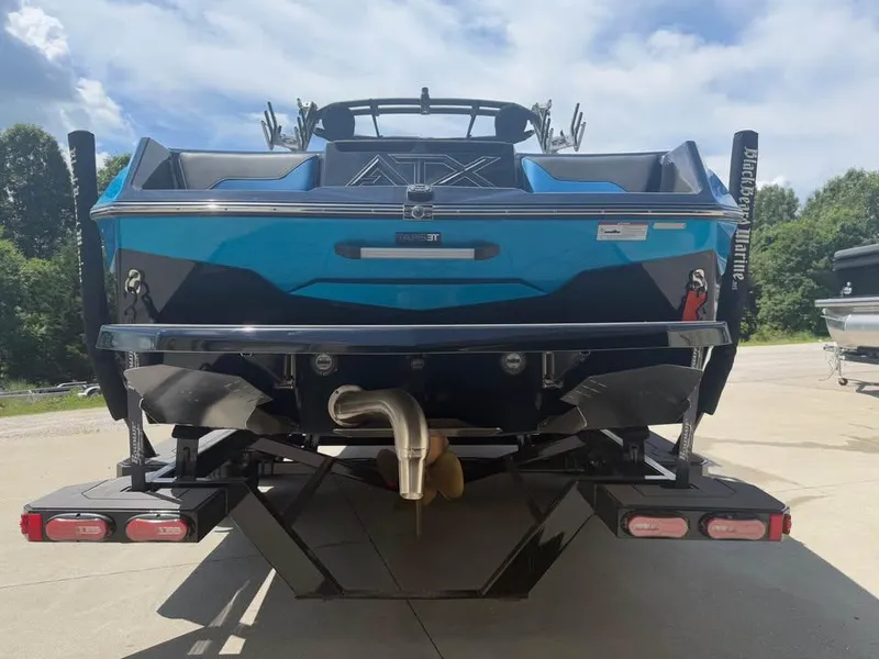 Slide: The Image of 2023 ATX Surf Boats 24 Type-S, rear view, blue and black design, parked outdoors. - 4