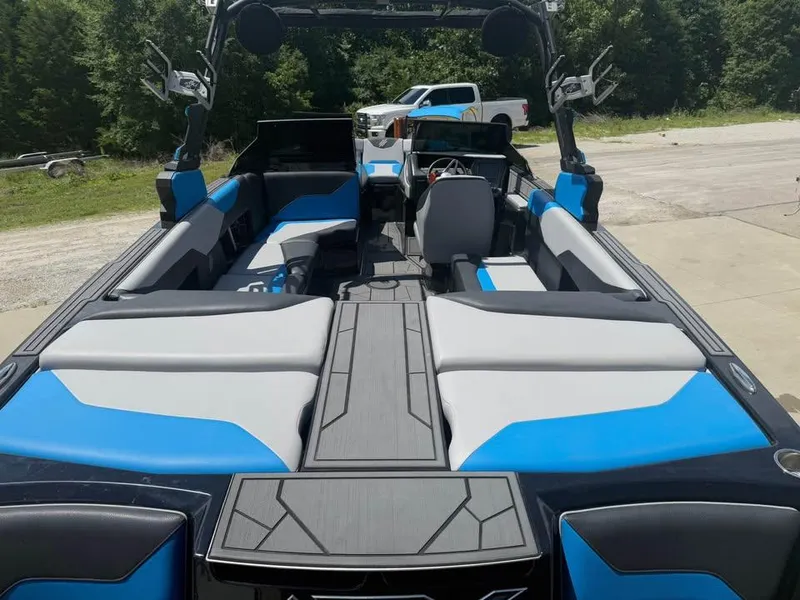 Slide: The Image of 2023 ATX Surf Boats 24 Type-S interior with blue and gray seating, parked outdoors. - 6