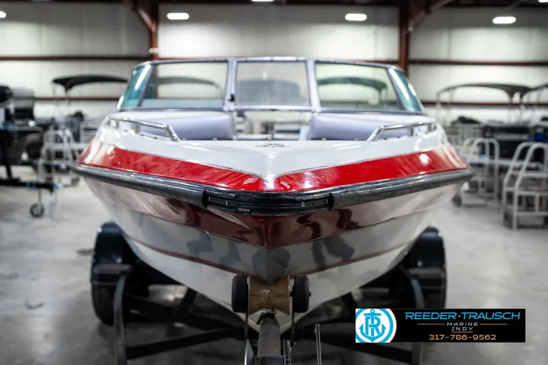 Slide: The Image of 1991 Caravelle I2300CC boat with red stripe in indoor showroom. - 3