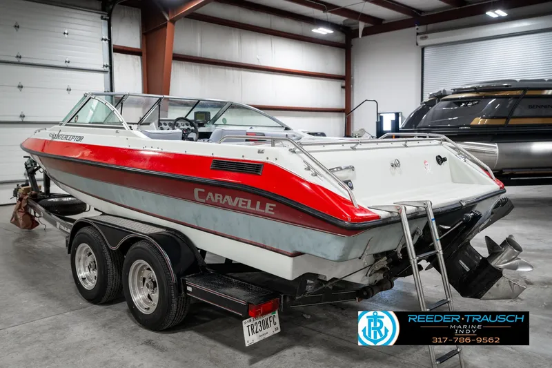 Slide: The Image of 1991 Caravelle I2300CC boat in a garage, red and white design, on a trailer. - 8