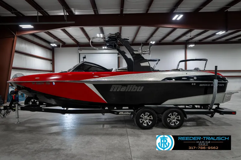 Slide: The Image of 2017 Malibu Wakesetter 25 LSV boat in a warehouse, red and black design. - 4