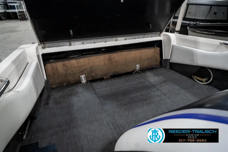 Slide: The Image of 1997 Malibu Response boat interior with open storage compartment, gray carpet, and white seating. - 25