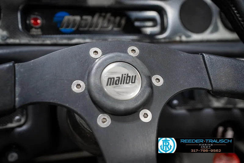 Slide: The Image of Steering wheel of a 1997 Malibu Response boat with logo and dashboard details. - 28