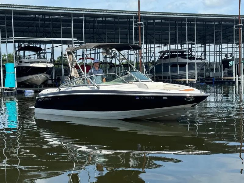 Slide: The Image of 2002 Cobalt 240 boat docked in marina, calm water, overcast sky. - 0