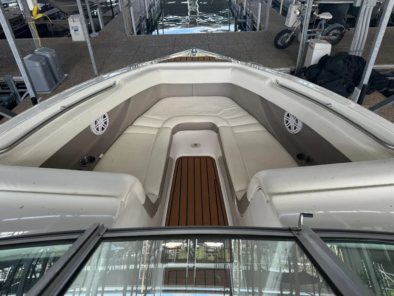 Slide: The Image of 2002 Cobalt 240 boat interior with cushioned seating and wood flooring at a dock. - 8