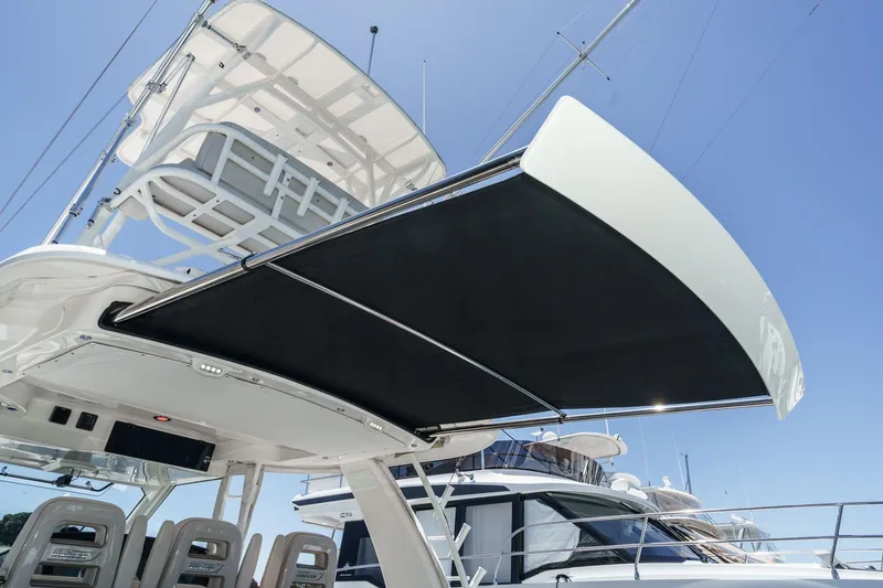 Slide: The Image of 2017 Boston Whaler 42 OUTRAGE boat with extended sunshade and seating, under clear blue sky. - 26