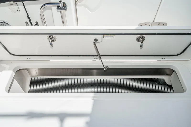 Slide: The Image of Open storage compartment on 2017 Boston Whaler 42 OUTRAGE boat, featuring secure latches and grid mat. - 29