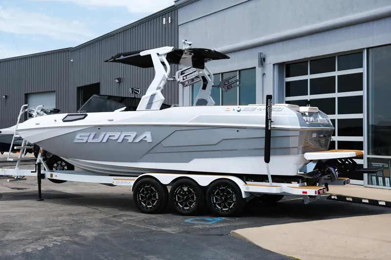 Slide: The Image of 2025 Supra SE450 boat on trailer outside a modern building. - 3