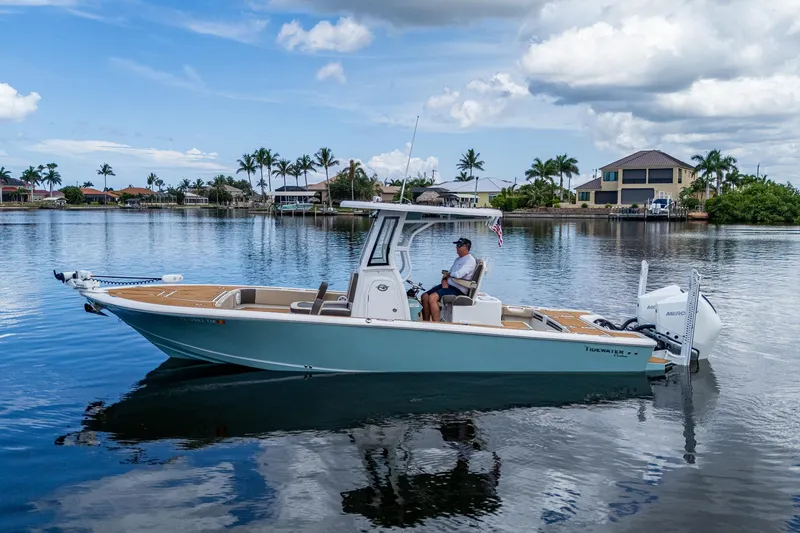 The Image of 2023 Tidewater 2700 Carolina Bay boat on calm water, with a person at the helm. - 1