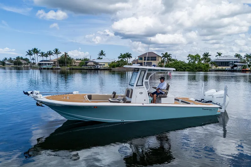 Slide: The Image of 2023 Tidewater 2700 Carolina Bay boat on calm water, with scenic background. - 2