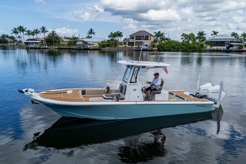 Slide: The Image of 2023 Tidewater 2700 Carolina Bay boat on calm water, surrounded by waterfront homes and palm trees. - 3