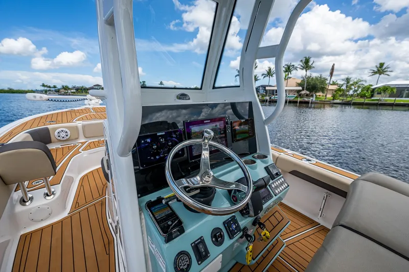 Slide: The Image of 2023 Tidewater 2700 Carolina Bay boat interior with modern dashboard and scenic water view. - 47
