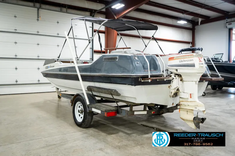 Slide: The Image of 1987 Hurricane 176 Deck Boat with Johnson outboard motor on trailer in indoor storage. - 10
