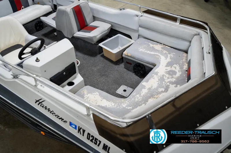Slide: The Image of 1987 Hurricane 176 Deck Boat interior with worn seating and steering console. - 13