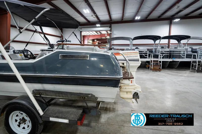 Slide: The Image of 1987 Hurricane 176 Deck Boat in showroom with other boats, Reeder-Trausch Marine logo visible. - 39