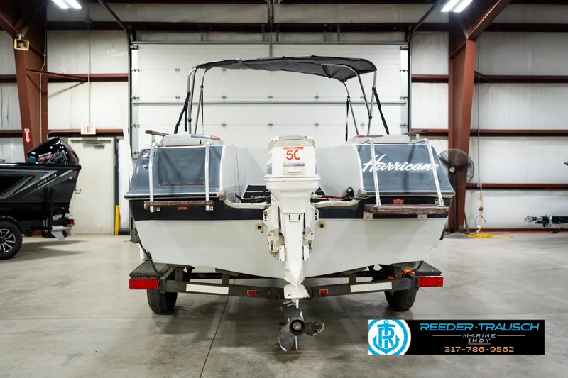 Slide: The Image of 1987 Hurricane 176 Deck Boat in a garage, rear view with visible outboard motor. - 9