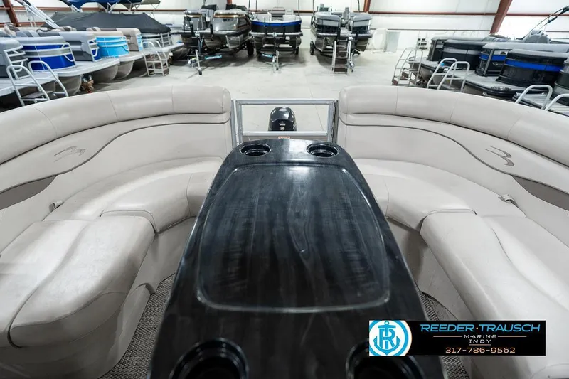 Slide: The Image of 2018 Bennington 20 SSRX pontoon boat interior with seating and table, displayed in showroom. - 18