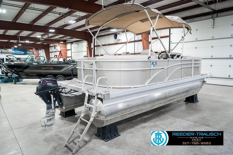 Slide: The Image of 2018 Bennington 20 SSRX pontoon boat in showroom with canopy and outboard motor. - 8