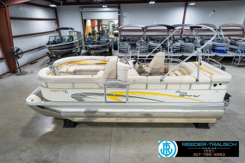 Slide: The Image of 2005 Bennington 2050 pontoon boat in showroom, featuring beige seating and yellow accents. - 10
