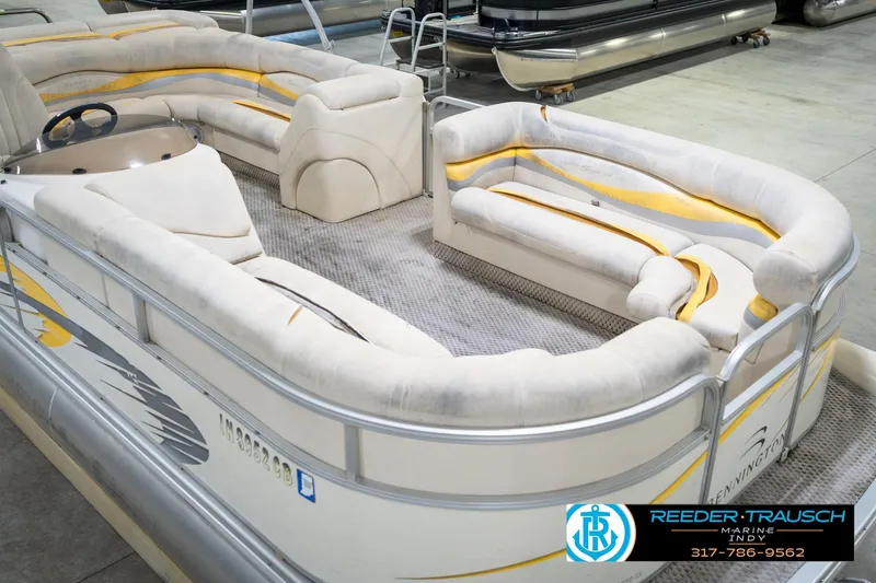 Slide: The Image of 2005 Bennington 2050 pontoon boat with plush seating, displayed indoors at Reeder-Trausch Marine. - 12