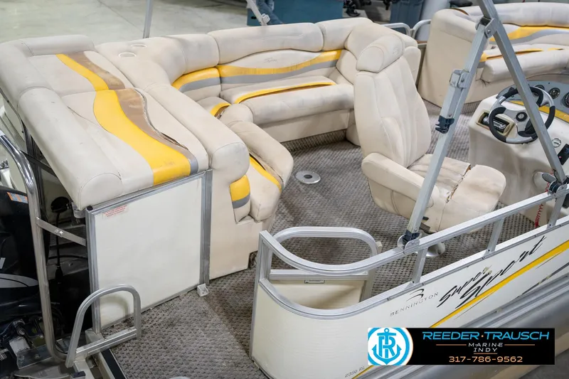 Slide: The Image of 2005 Bennington 2050 boat interior with beige and yellow seating, steering console, and carpeted floor. - 13