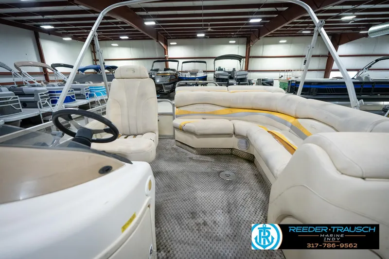 Slide: The Image of 2005 Bennington 2050 pontoon boat interior with beige seating in a showroom. - 25