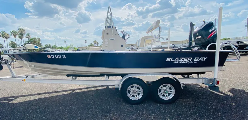 Slide: The Image of 2014 Blazer Bay 2200 Professional boat on trailer under a partly cloudy sky. - 3