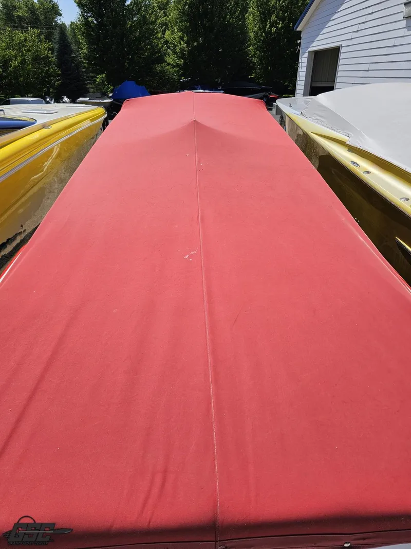 Slide: The Image of Red-covered Sonic USA 45SS boat, 2004 model, parked outdoors between other boats. - 31