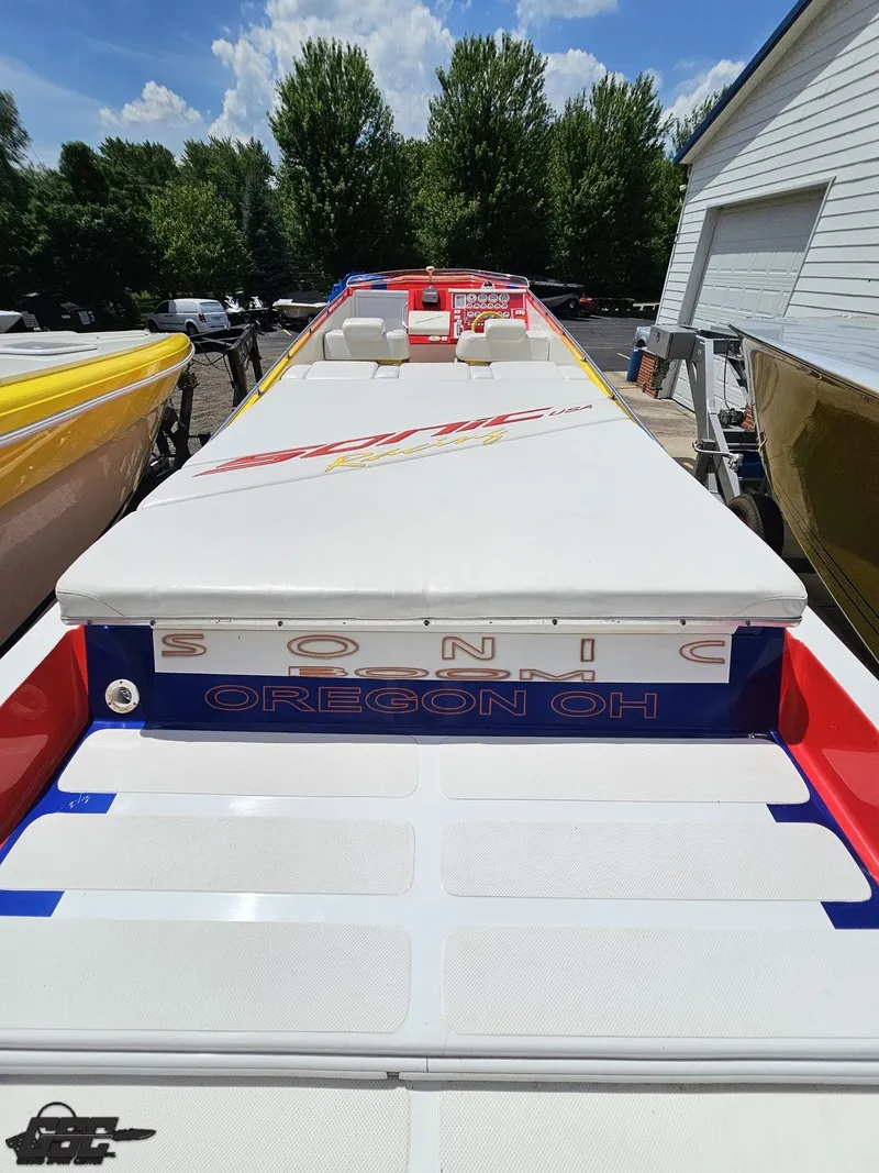 Slide: The Image of 2004 Sonic USA 45SS speedboat with white deck, parked outdoors under blue sky. - 32