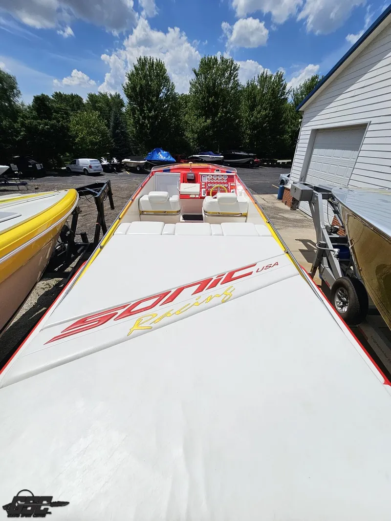Slide: The Image of 2004 Sonic USA 45SS speedboat with white and red design, parked outdoors under a blue sky. - 33