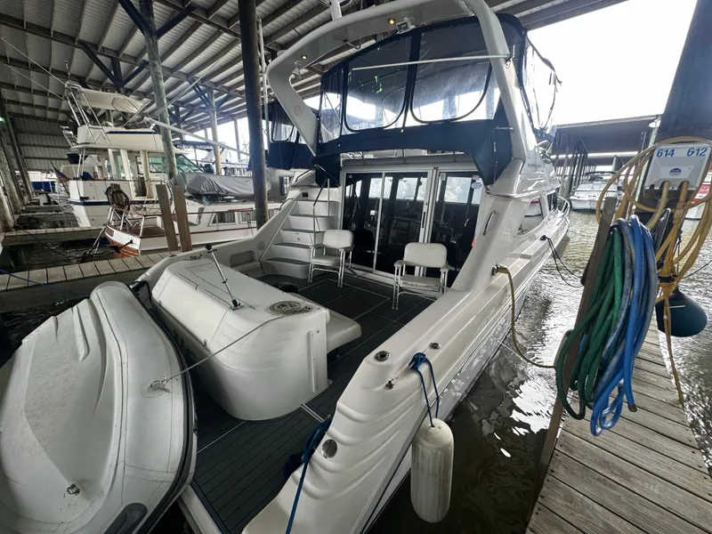 Slide: The Image of 1996 Sea Ray 440 Express Bridge docked in a marina, featuring spacious deck and seating. - 11