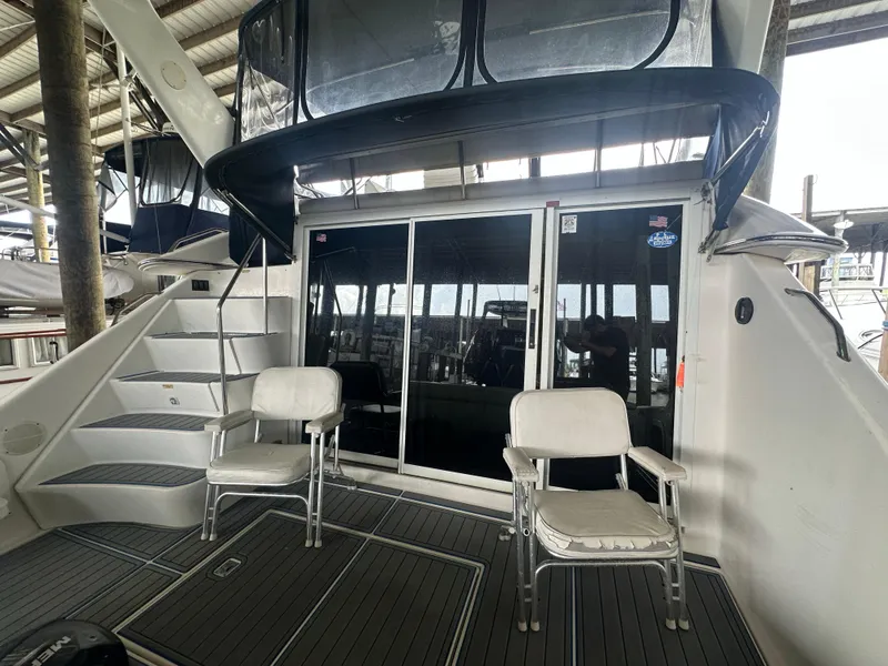 Slide: The Image of 1996 Sea Ray 440 Express Bridge yacht deck with chairs and sliding glass doors. - 12